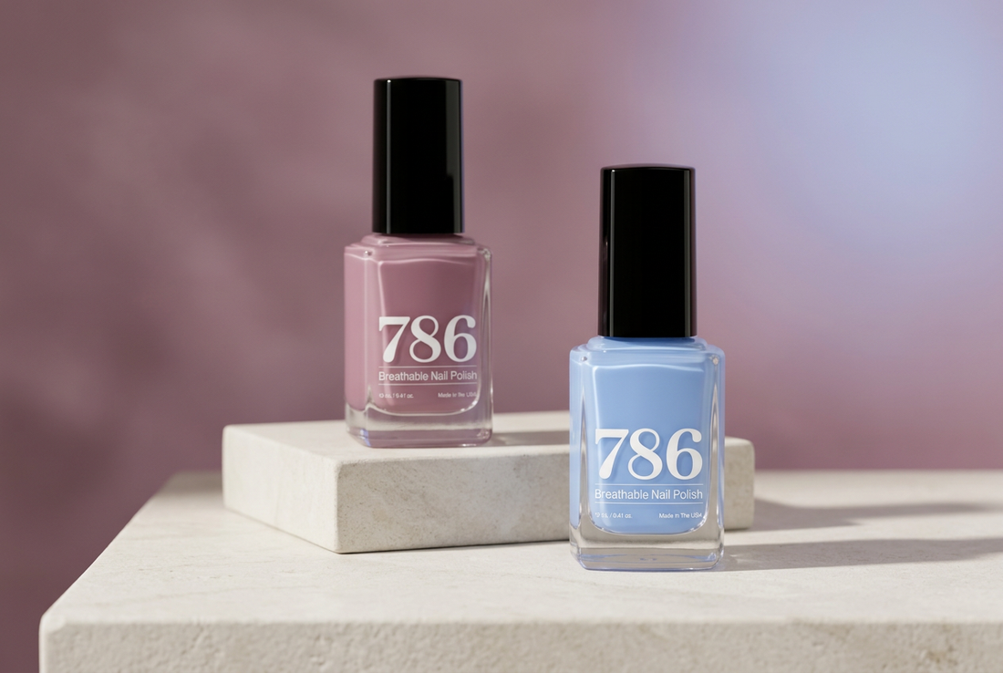 786 Cosmetics Kashmir mauve and Azores periwinkle nail polish bottles with black caps arranged on an off-white vanity against a soft mauve and blue background.