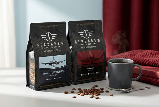 AeroBrew Wake Turbulence Medium Roast and Afterburner Blend Dark Roast coffee bags beside a charcoal mug of coffee on a light gray table.