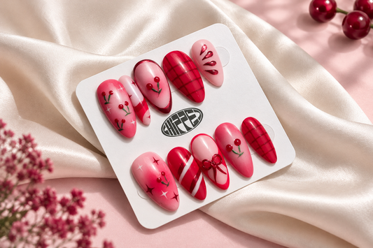 Chipped Social Cherrysh Me pink and red press-on nails with cherry, bow, and star designs displayed on a white card over ivory satin.