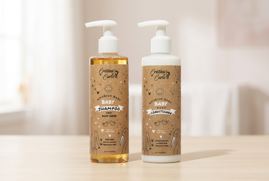  Cristina’s Curls Nourishing Baby Shampoo and Body Wash beside Nourishing Baby Conditioner in white-pump bottles with kraft-colored labels on a cream surface.