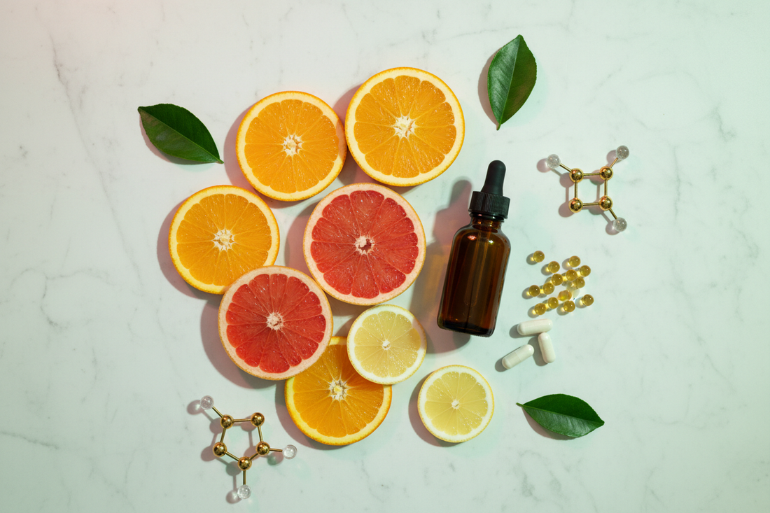 Fresh sliced oranges, a dark supplement bottle, and liposomal capsules on white marble — liposomal vs. regular vitamin C absorption science