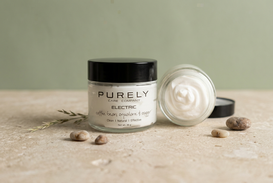  PURELY Electric tallow skincare jar beside an open jar of cream on a pale stone surface against a muted sage background.