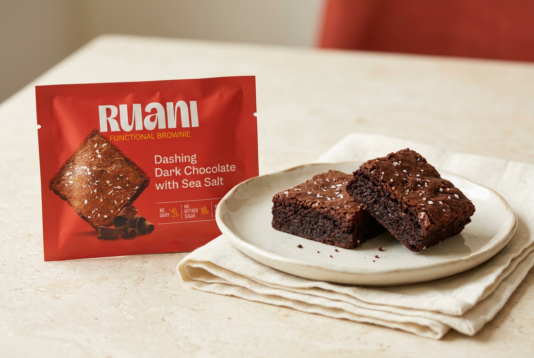  RUANI dark chocolate sea salt brownie wrapper beside two brownie pieces on a cream plate with ivory linen.