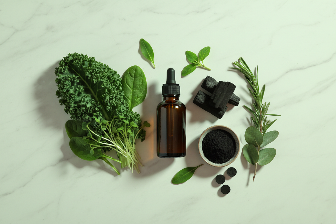 Dark supplement bottle, fresh spinach, kale, and green botanicals on white marble — cellular detox and toxin burden science