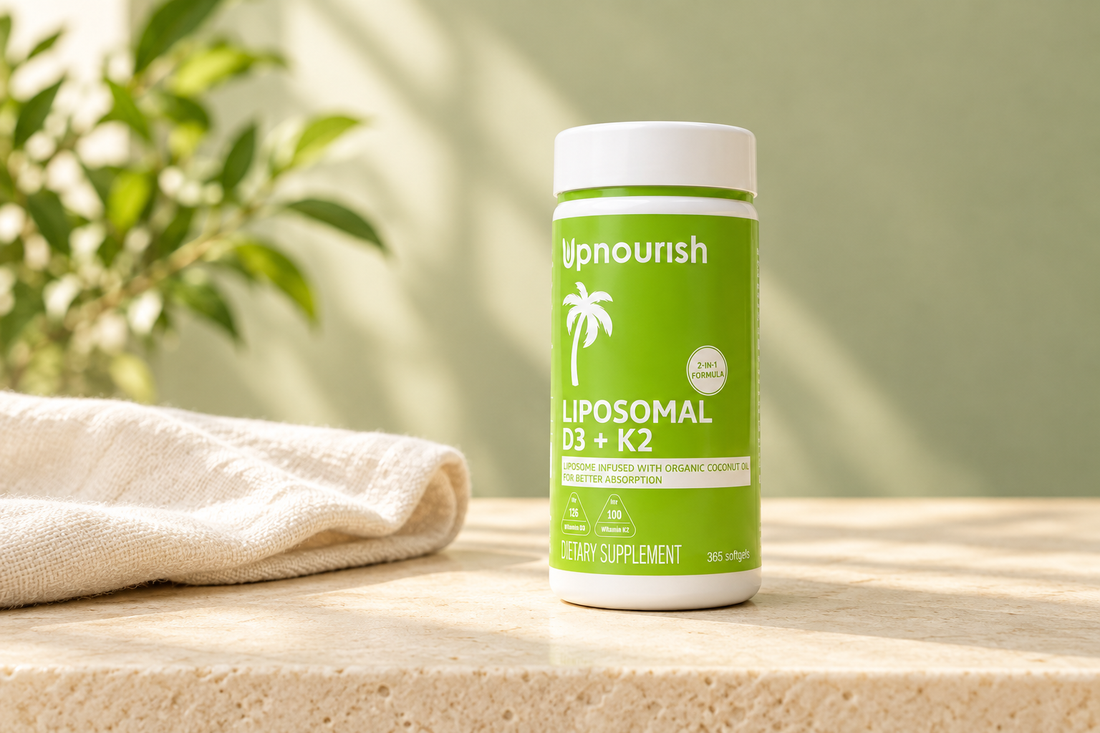 UpNourish Liposomal D3 and K2 supplement bottle with a citrus-green label beside ivory linen on a warmly lit cream surface.