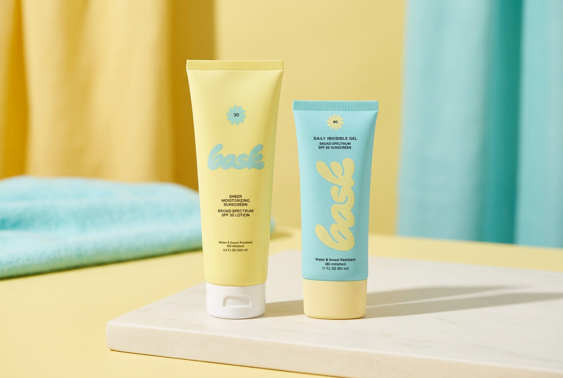 Yellow Bask SPF 30 Sheer Moisturizing Lotion and aqua Daily Invisible Gel SPF 40 sunscreen tubes on an ivory surface.