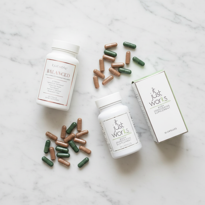 Image 2: Flat lay of Balanced and Fresh supplement bundle with brown and green capsules on white marble surface