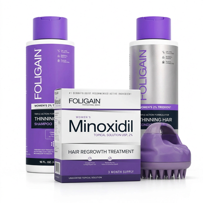FOLIGAIN women's scalp care bundle with shampoo and conditioner behind a boxed 2% minoxidil three-month supply and purple scalp massager.
