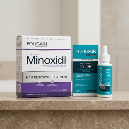 Women's FOLIGAIN minoxidil and 2dDR serum duo arranged on a neutral stone bathroom shelf.