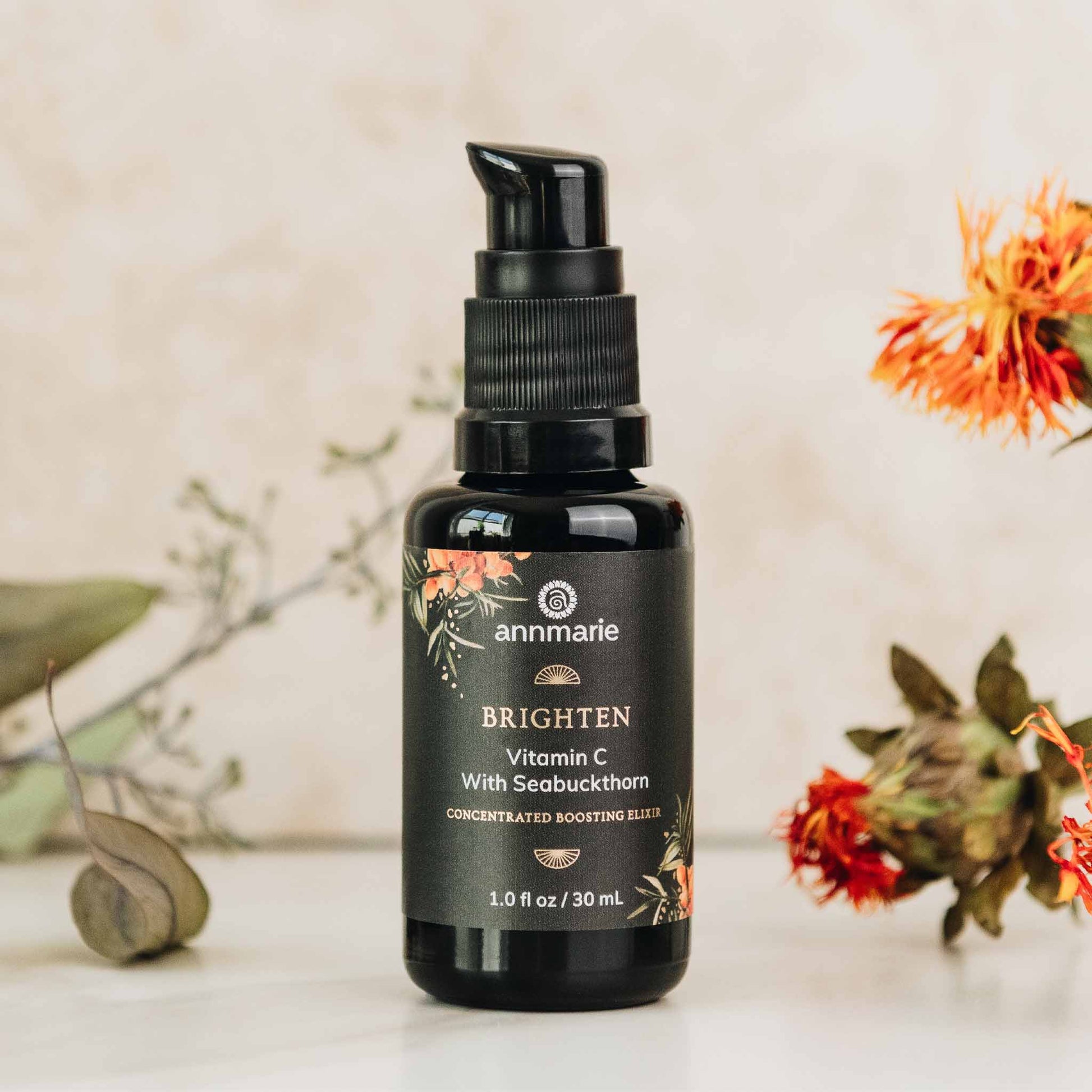 Black bottle of annmarie skincare serum with decorative elements on a light background