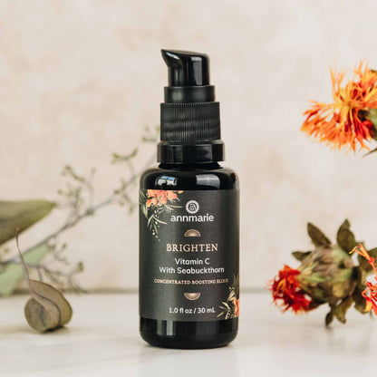 Black bottle of annmarie skincare serum with decorative elements on a light background